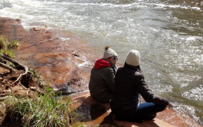 Two people sitting near a river