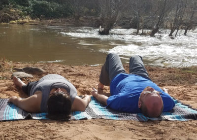 Two people practicing Yoga near a river