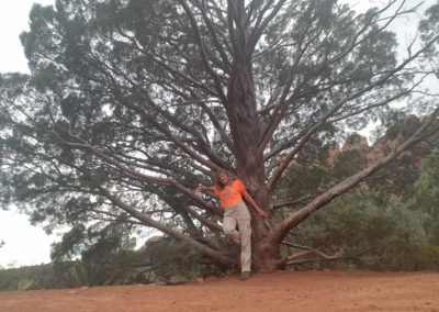 Margareth in an orange top near a tree